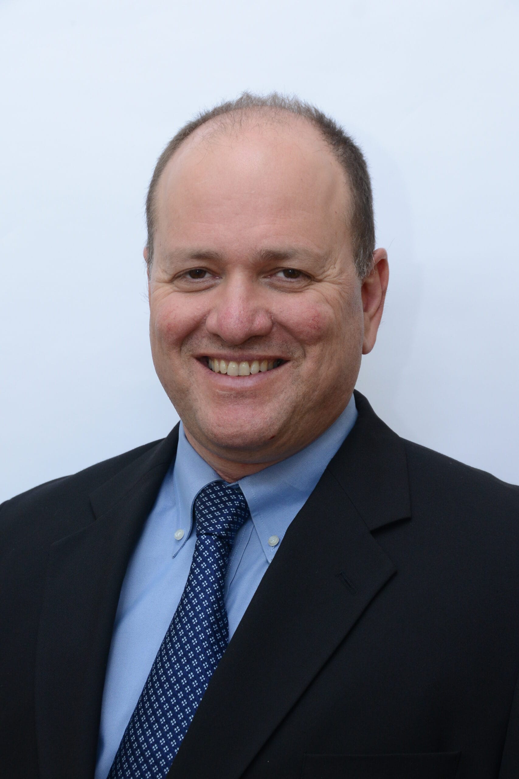 Headshot of a smiling man in a suit and tie.